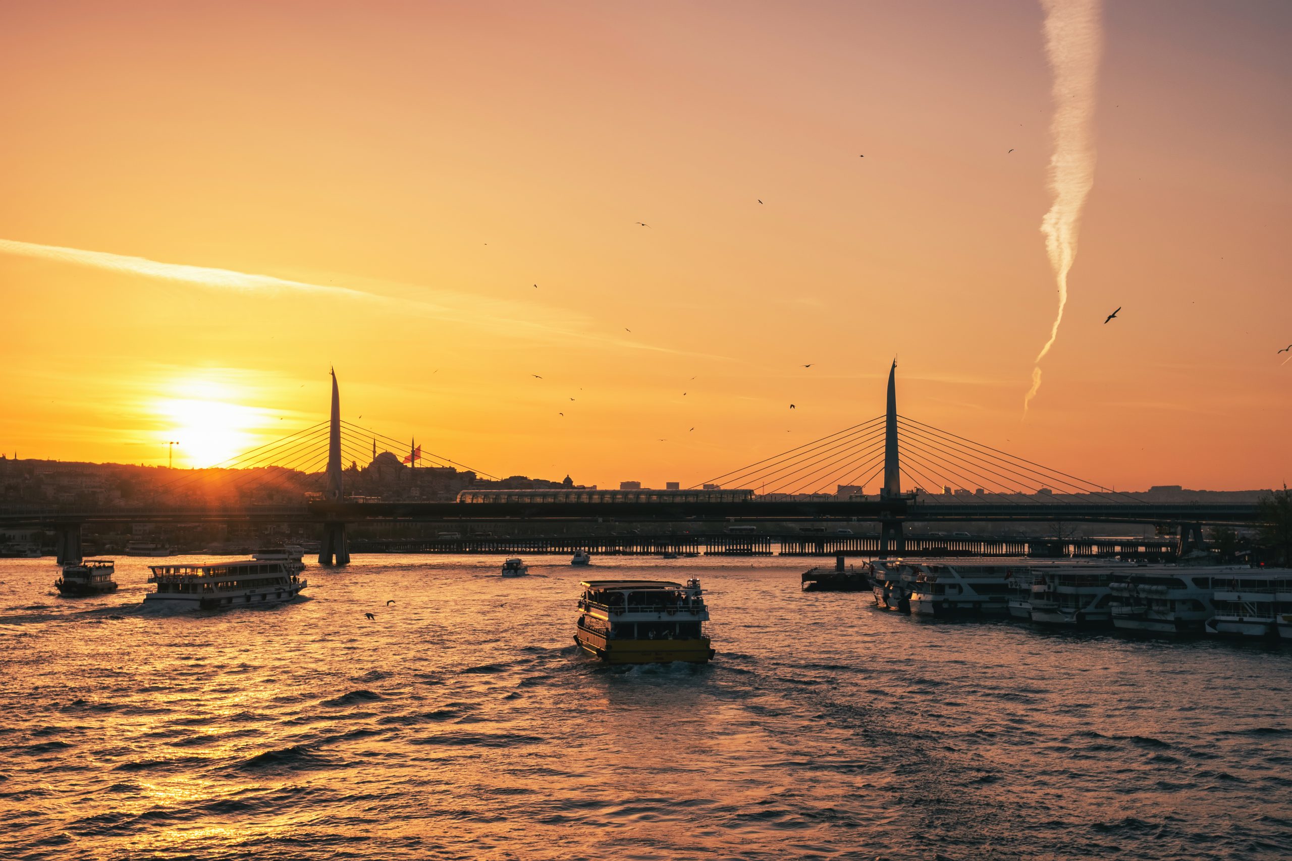 Outstanding yellow sunset of the Turkish sea, flying seagulls and boats swimming across